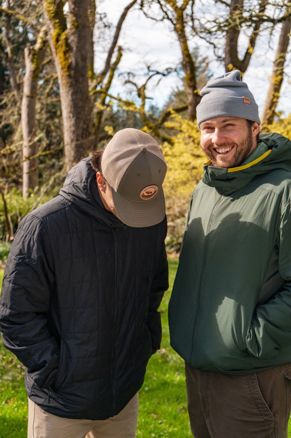 Two friends laughing in a Willamette trucker and gray beanie