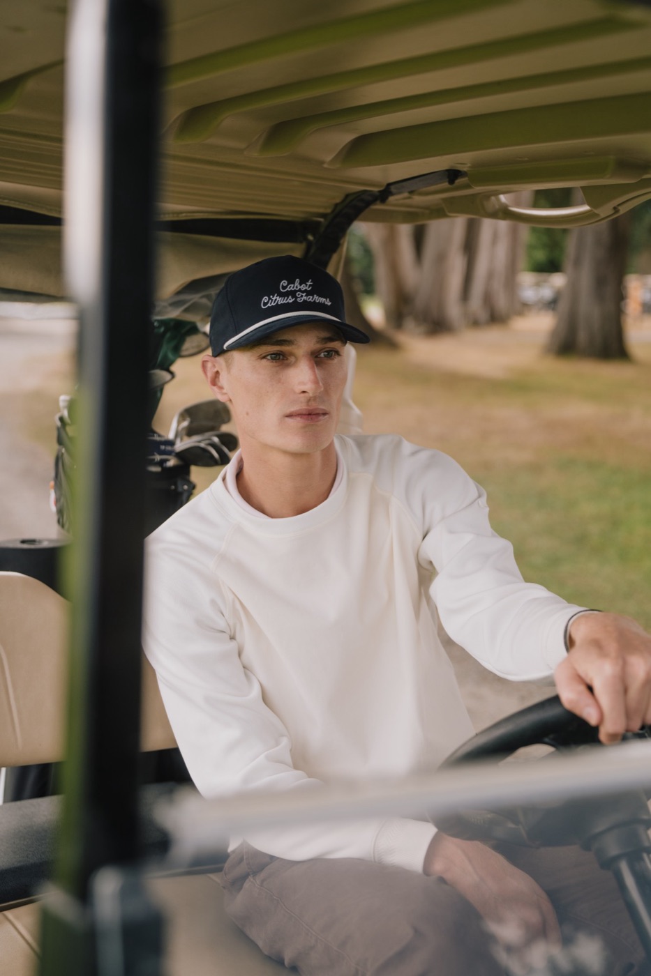 Golfer in a Cabot Citrus Farms rope cap driving a golf cart
