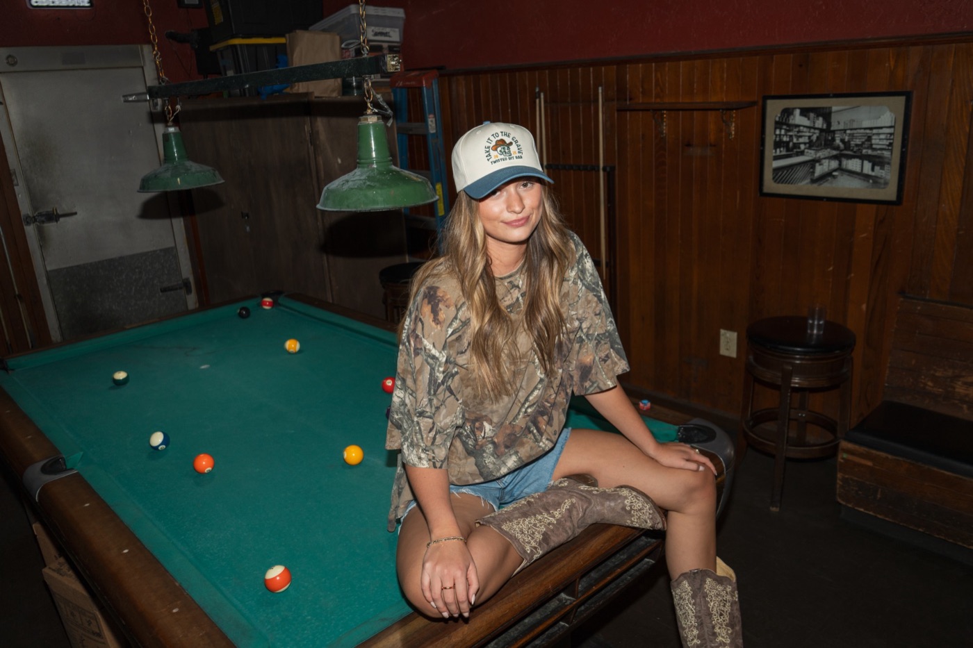 Model in a Take It to the Grave cap sitting on a pool table