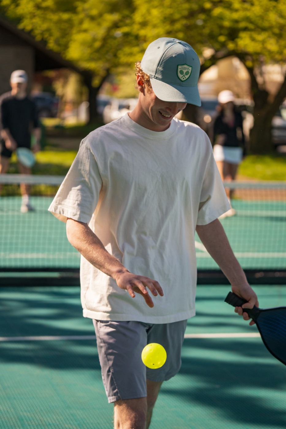Player in a racquet club cap bouncing a ball on the court