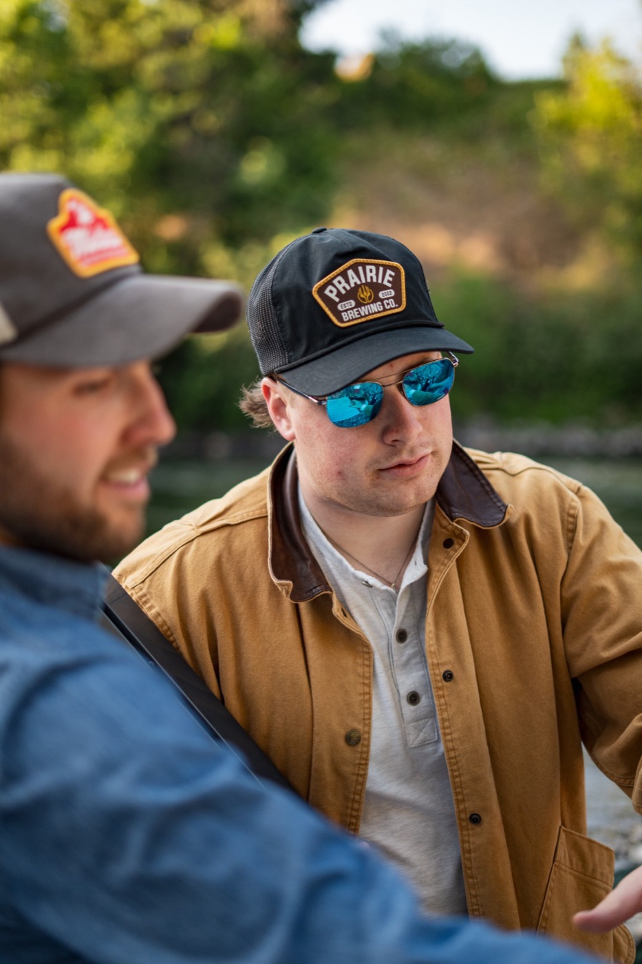 Man in a Prairie Brewing cap and sunglasses by the river