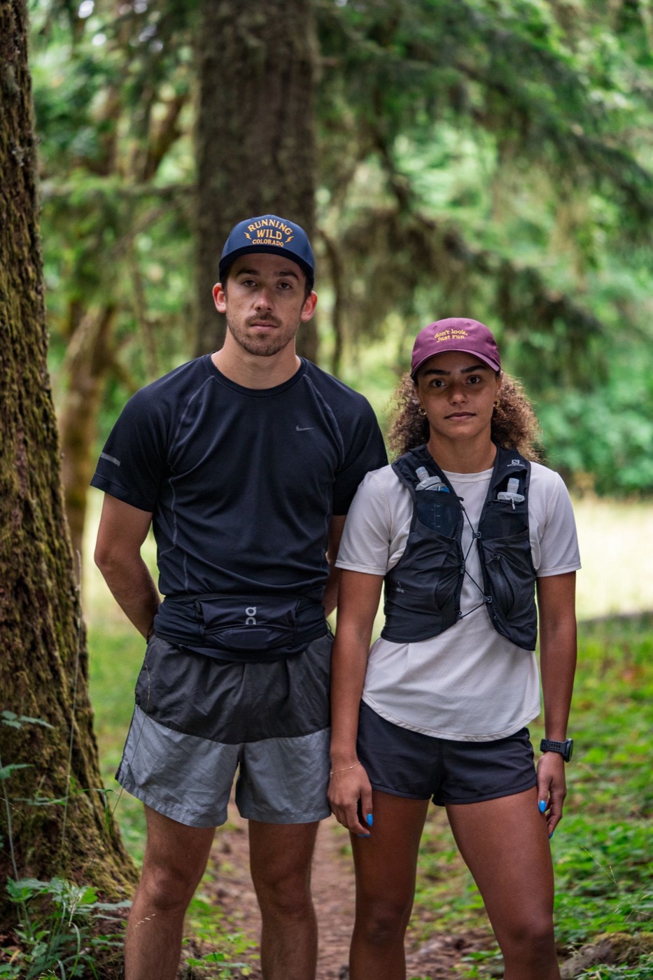 Both runners standing on a forest trail
