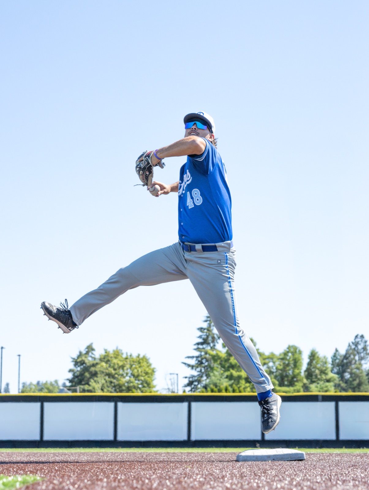 Pitcher mid-throw against a blue sky