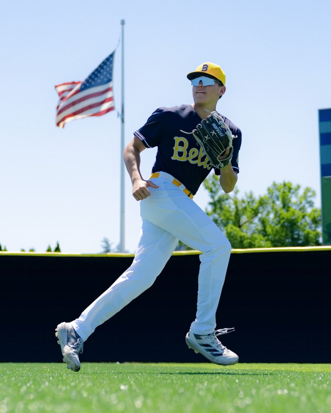 Bellingham Bells outfielder running in front of an American flag
