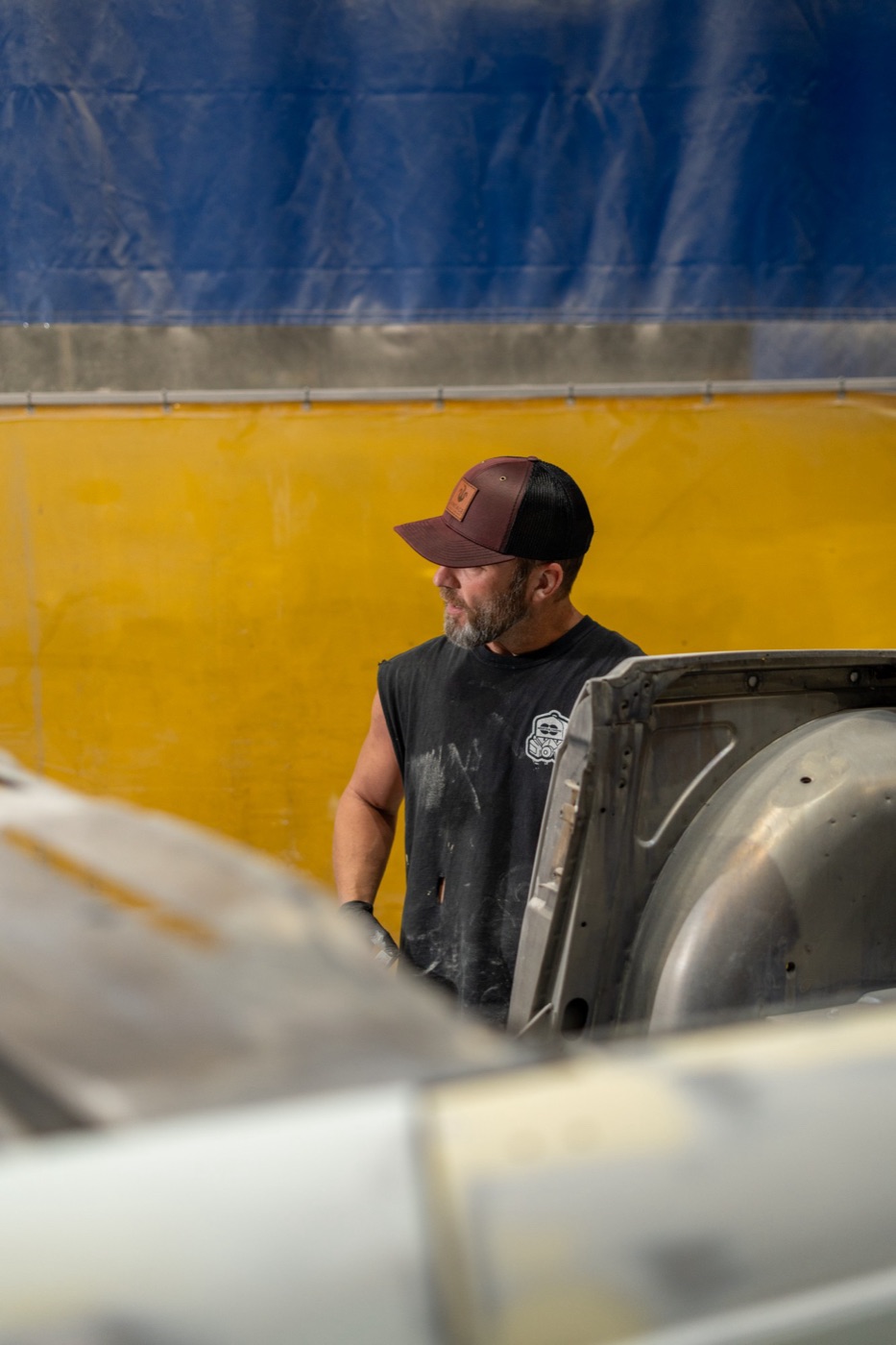 Restoration worker in a maroon trucker against a blue and yellow backdrop